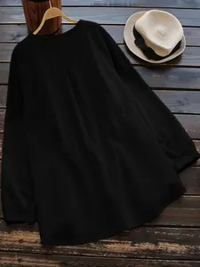 Detailed back view of a black loose-fit cotton linen blouse on a wooden background