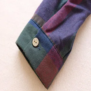 Gros plan sur le poignet d'une chemise à carreaux avec un bouton en bois et texture fine