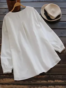 Detail view of a white slub cotton linen loose blouse with a round neck and rustic style