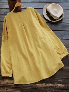 Back view of a yellow loose cotton linen tunic showing pleated detail and slub texture