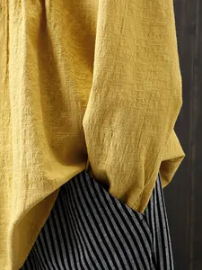Detail of yellow slub cotton linen blouse texture and striped pants pocket.