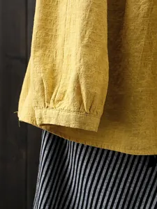 Close-up of yellow slub cotton linen blouse showing fabric texture and pleated cuff details