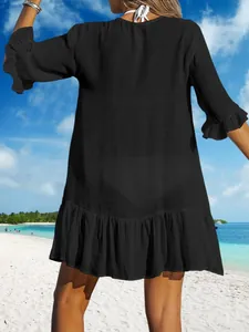 Rückansicht eines schwarzen Strandkleides mit Rüschensaum an einem tropischen Sandstrand