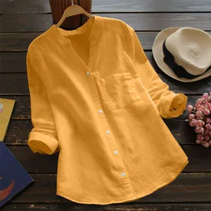Gros plan d'une chemise en lin et coton jaune moutarde sur un fond de bois sombre.