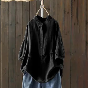 Detail view of a loose black long sleeve stand collar shirt with textured fabric