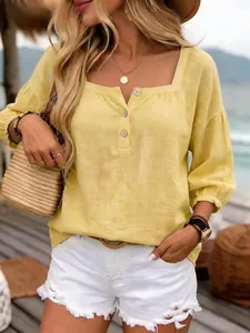 Dettaglio di una maglia in lino gialla con scollo quadrato e bottoni in ambiente esterno soleggiato.
