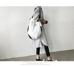 Woman wearing long-sleeved blue and white vertical striped shirt with white tote bag