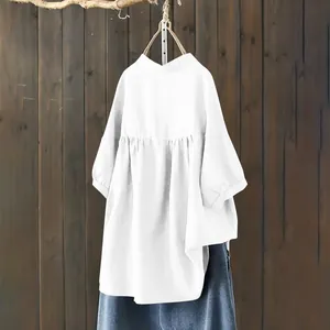 Detailed view of an oversized white mandarin collar shirt hanging on a wooden branch