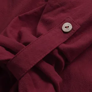 Détail de tissu en lin bordeaux montrant une patte de manche boutonnée et sa texture