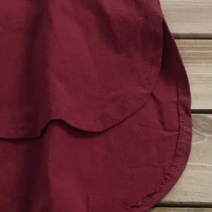 Gros plan de l'ourlet arrondi d'une chemise en lin rouge vin pour femmes