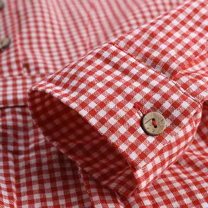 Gros plan d'un poignet de chemise à carreaux rouge et blanc avec bouton en bois