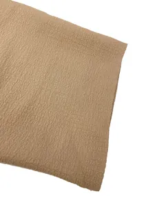 Detailed macro shot of light brown textured crepe fabric for women's casual solid color shirt