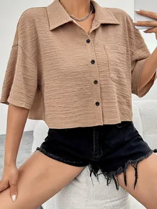 Close-up of a textured beige cropped button-up shirt featuring a front pocket and mid-sleeves