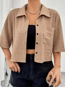 Close-up detail of a textured khaki button-up short sleeve cropped shirt with chest pocket