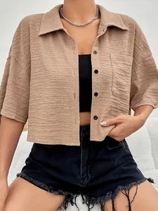 Close-up of khaki crinkle texture cropped shirt with black buttons and pocket detail.