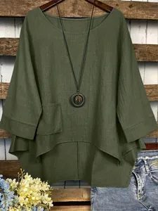 Vue détaillée d'une blouse en lin vert foncé avec un ourlet irrégulier et poche.