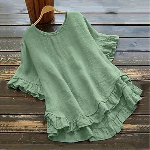 Détail d'une blouse en coton et lin vert sauge avec manches et ourlet volantés.