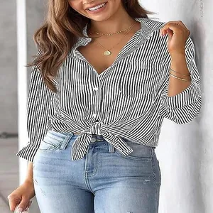 Detail view of a woman wearing a black and white striped shirt tied at the waist