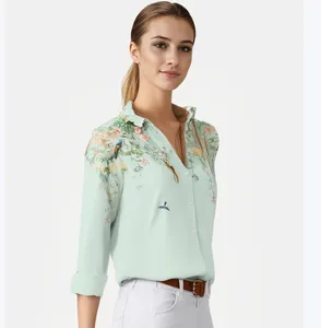 Detailweergave van de elegante bloemen- en vogelprint op de lichtgroene damesblouse