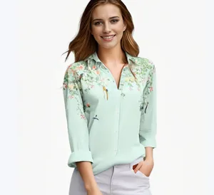 Detailopname van een lichtgroene blouse met stijlvolle bloemen- en vogelprints.
