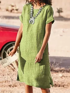 A detail shot showing the side slit of a casual green short sleeve midi dress for women
