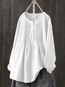 Macro view of a white linen cotton blouse with elegant pleated front and button details.