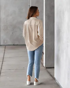 Rear view of a casual woman wearing a brown vertical striped long-sleeved shirt and jeans