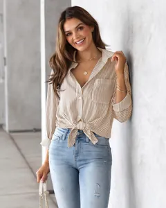 Detailed view of women's striped long sleeve shirt tied at waist in a modern setting