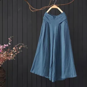 Elegante blauwe katoen linnen culotte broek hangend tegen een rustieke donkere houten muur