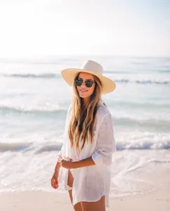 Mujer hermosa con una camisa de playa de tela crepé blanca en una playa soleada junto al mar