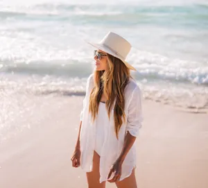 Modelo con camisa de playa blanca de tela arrugada en una playa soleada durante el día