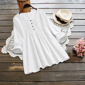 White cotton linen tunic shirt with pleated front and button detail on wooden background