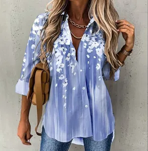 Macro detail showing the elegant white floral print on a blue long-sleeved blouse.