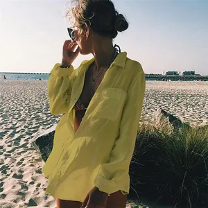 Mujer con camisa de playa amarilla texturizada en una playa soleada de la costa