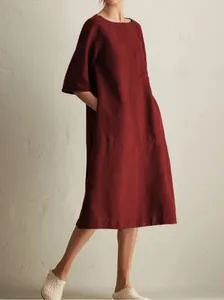 Detail view of a burgundy cotton linen midi dress with a round neck and side pockets.