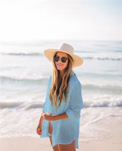 Elegante mujer con camisa playera azul claro en una playa soleada de estilo vacacional
