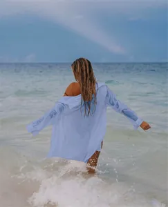 Vista trasera de una camisa de playa azul claro en tejido arrugado ante el mar.