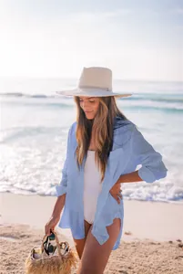 Camisa playera de textura azul claro sobre un bañador blanco en una playa soleada.