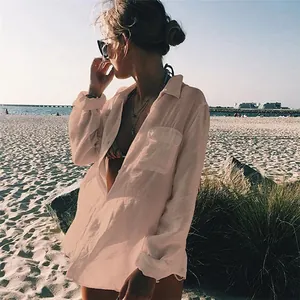 Mujer hermosa con camisa de playa rosa de tela arrugada en una playa de arena soleada