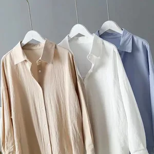 Texture detail of loose cotton linen long-sleeve shirts in beige, white, and blue.