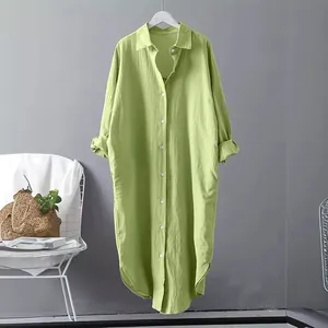 Front view of an avocado green oversized cotton linen long shirt dress hanging on a wall.