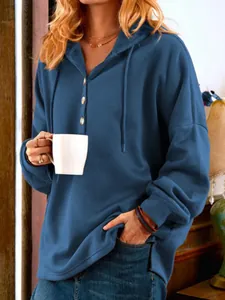Detailansicht eines blauen Kapuzenpullovers mit Polo-Ausschnitt, Knopfverschluss und Baumwollstoff.