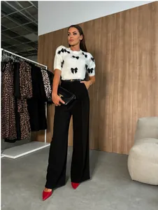 Vista completa de elegantes pantalones negros de pernera ancha y suéter con lazo.