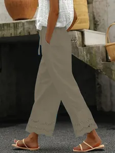 Detail of khaki casual cropped pants featuring intricate lace embroidery at the hem.