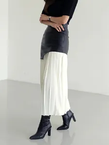 Dettaglio elegante della gonna a pieghe a vita alta con pannello in pelle nera