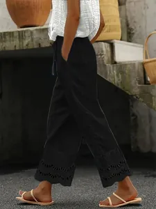 Detail view of women's black casual cropped pants with delicate lace eyelet hem