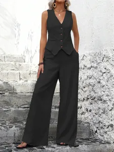 Full view of women's black vest suit set showcased on a model against a stone wall