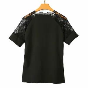 Dettaglio di t-shirt nera con inserti in pizzo floreale sulle spalle su stampella.