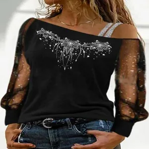 Detail of black off-shoulder top with rhinestone pattern and sheer sparkly mesh sleeves