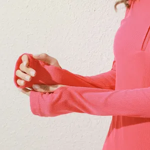Dettaglio della manica del vestito a coste rosa con foro per pollice e trama morbida